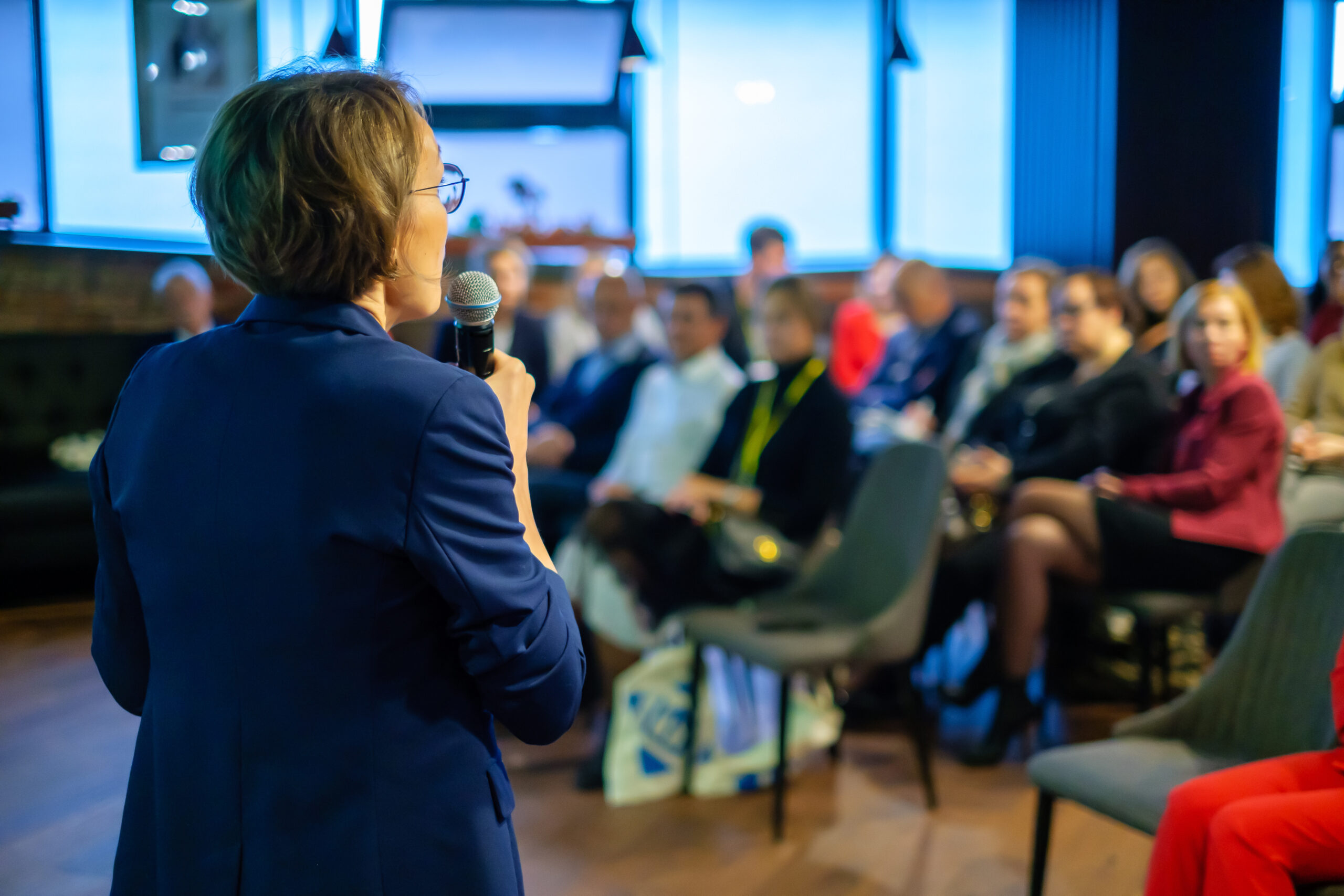 Picture of woman with speaking to an audience at a conference.
